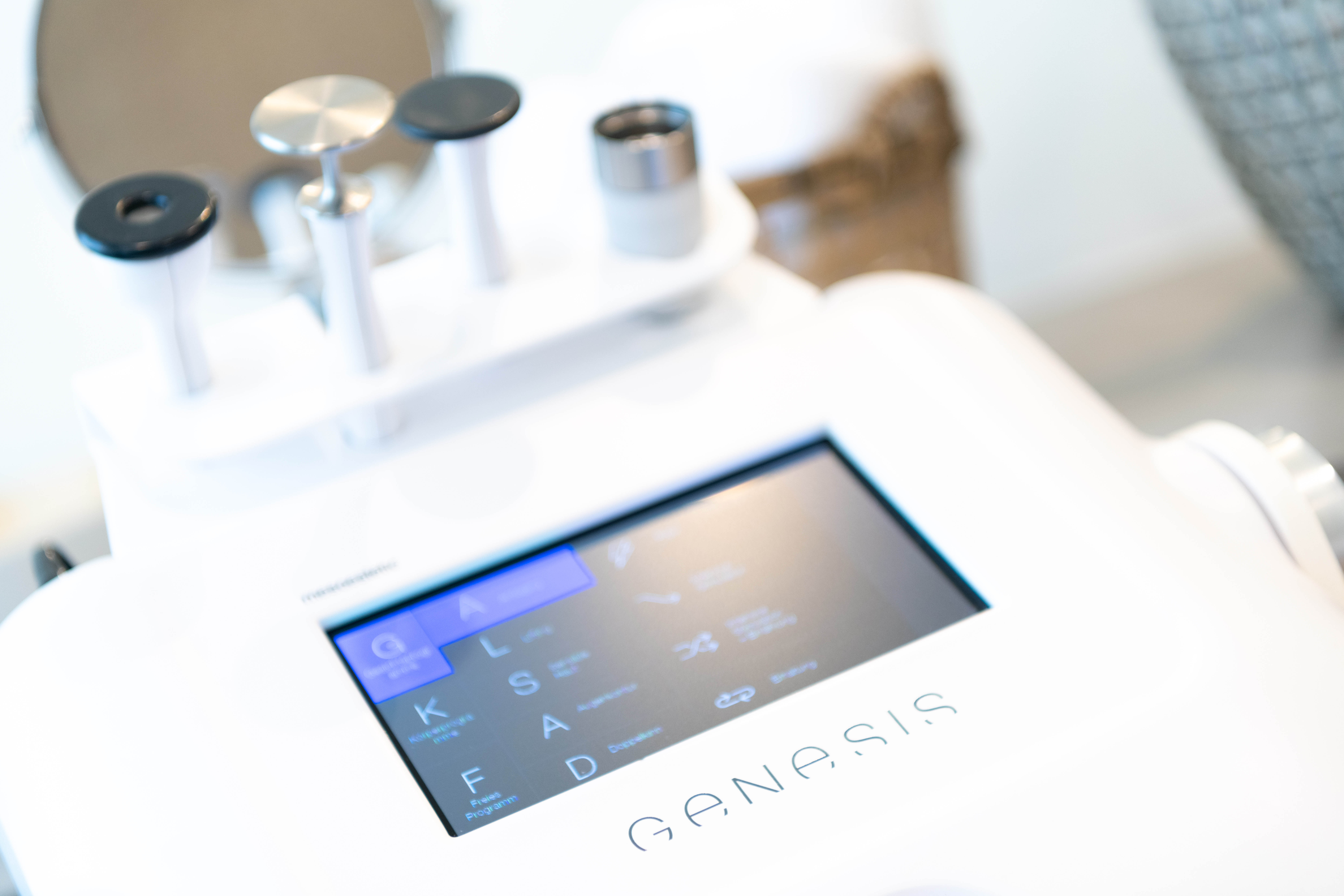 Modernes Behandlungsgerät „Genesis“ mit Touchscreen und verschiedenen Aufsätzen für kosmetische Anwendungen in Nahaufnahme.